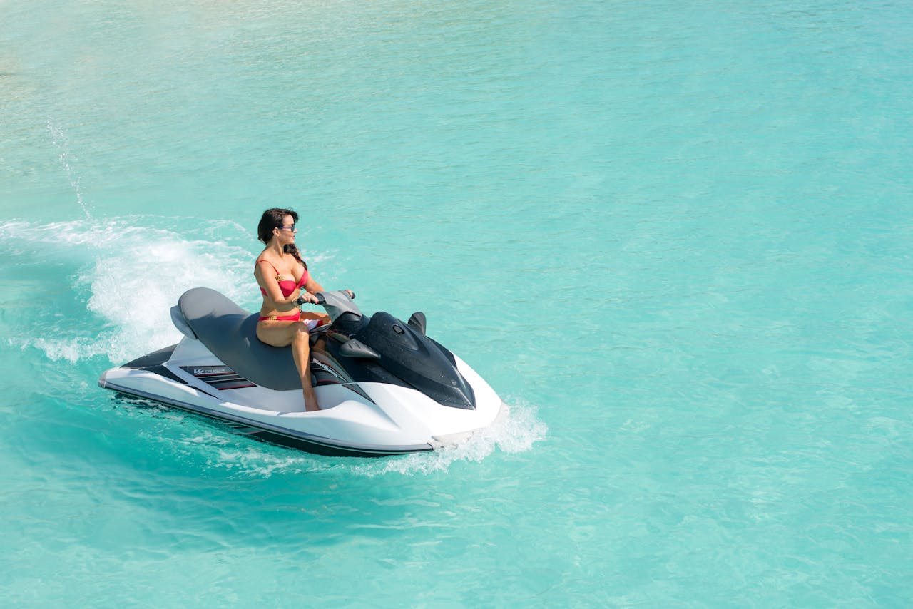 Vibrant image of a woman enjoying a jet ski ride in clear turquoise water.
