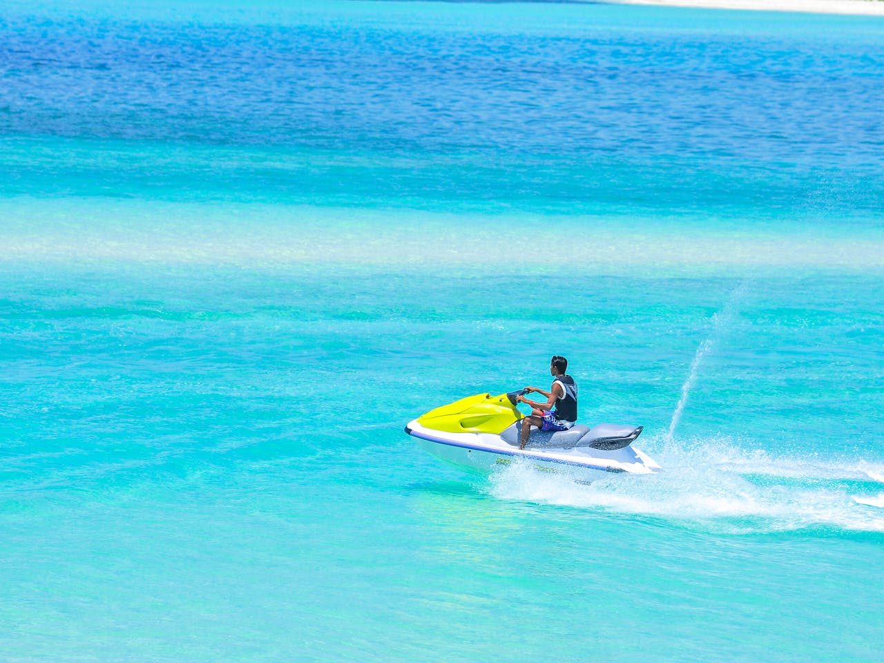 Experience thrilling jet ski ride in clear blue Maldives sea with bright skies.
